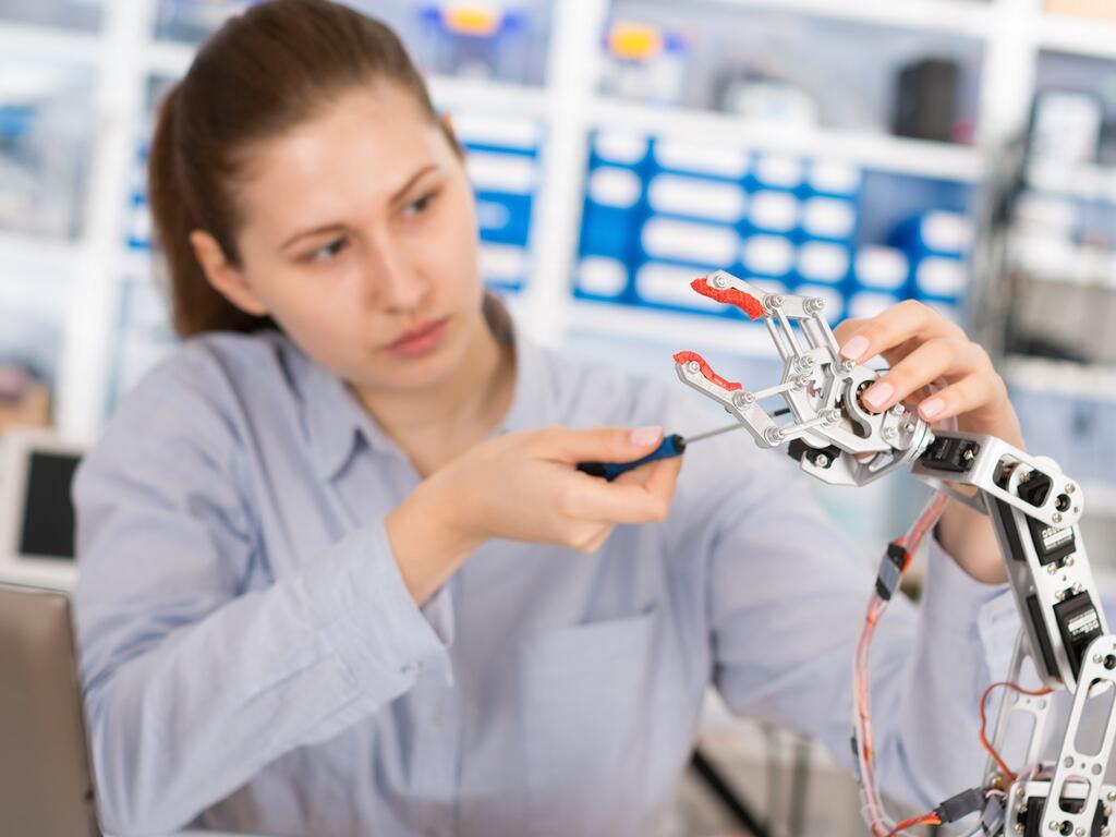 mujer trabajando con brazo de robot | Desafíos que tiene la carrera de ingeniería